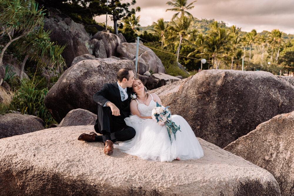 bride and groom sitting on a rock embracing - Townsville Wedding Photography by Jamie Simmons