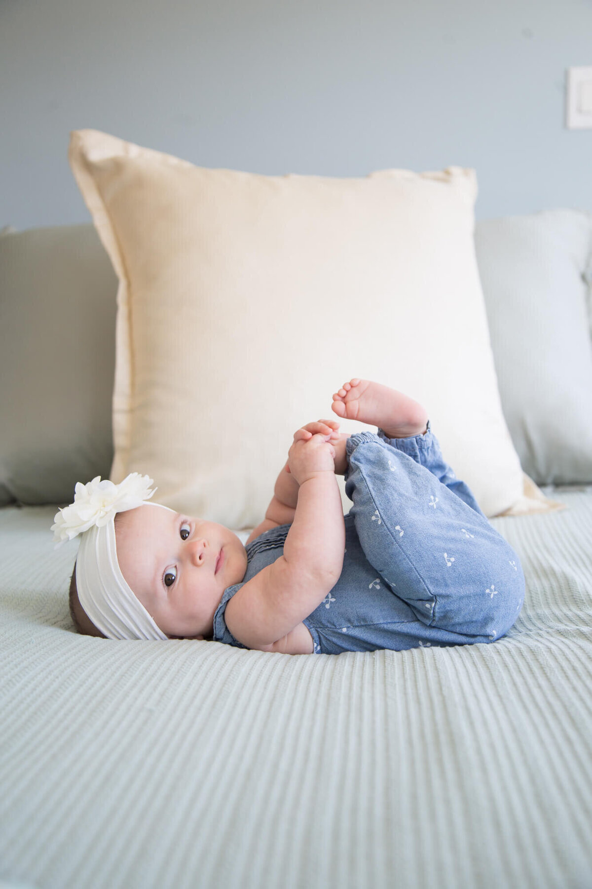 beautiful baby girl laying on a bed holdignn her toes