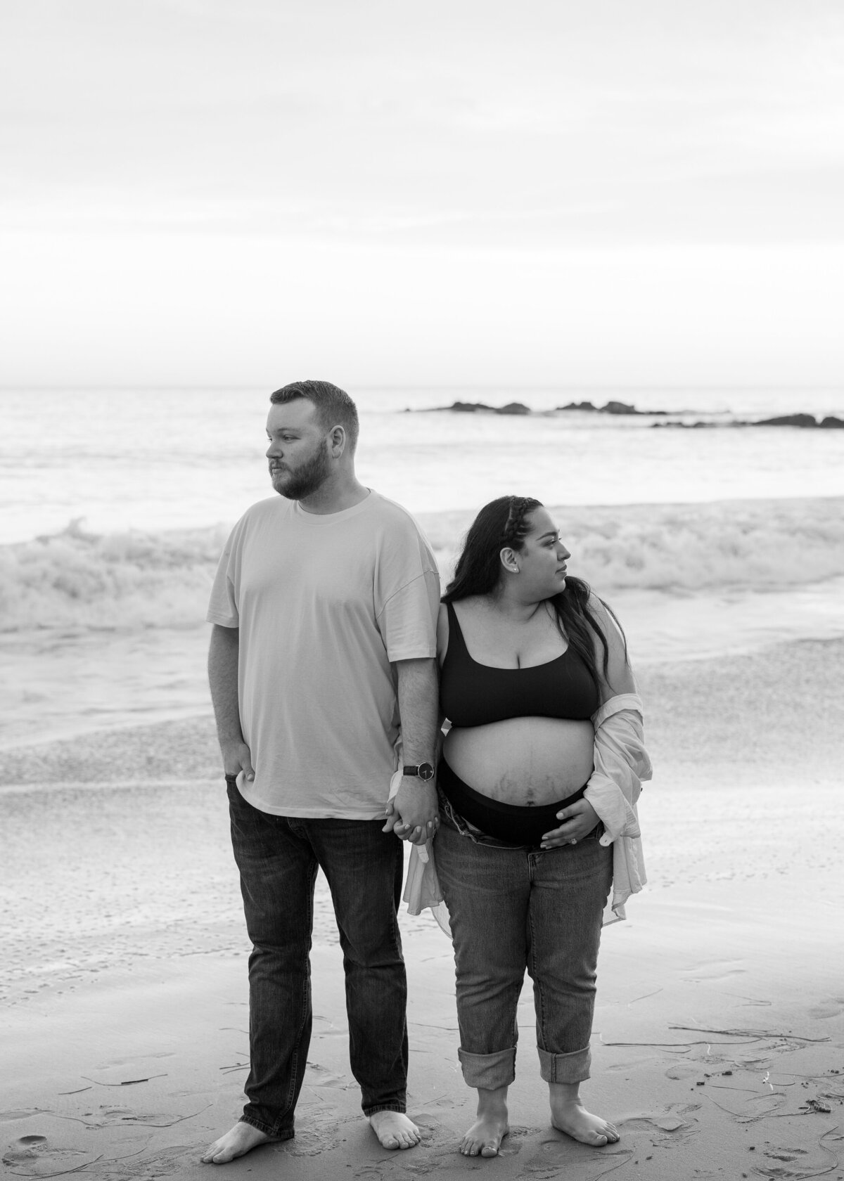 moody black and white maternity photo on the beach