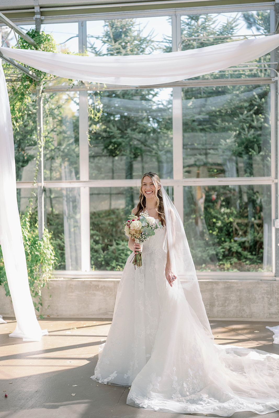 Solo full-body bridal portrait inside the greenhouse at The Ivy House in Saugatuck, Michigan.