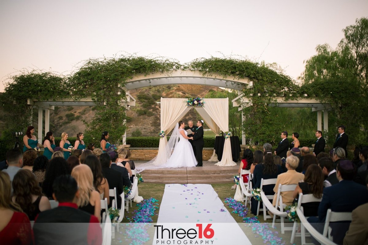 Bride and Groom hold hands during their wedding ceremony at the outdoor Black Gold Golf Club in Yorba Linda