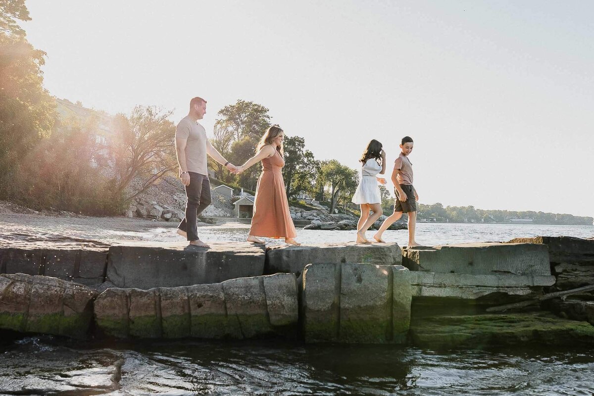Family of four walking on jetty at Huntington Beach during Cleveland family photography session.