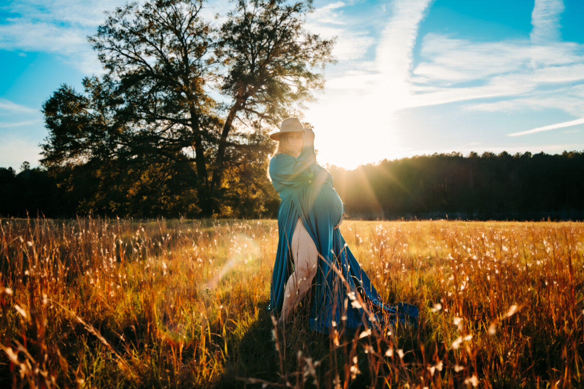 Pregnant mom in a field at sunset in a blue dress