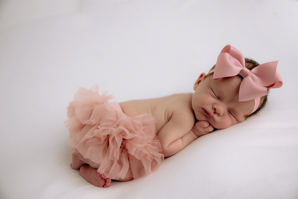 newborn photo of baby girl in pink tutu and pink hair bow