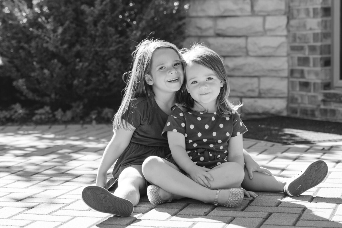 Black and white photo of two young sisters sitting cross-legged
