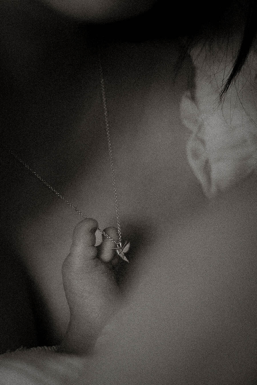 Artistic black and white newborn detail with a baby’s foot resting on mom’s necklace.