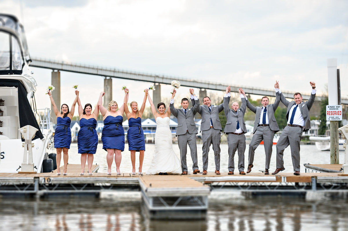 A happy wedding party cheer for joy on the docks outside of the Chesapeake Inn Restaurant.