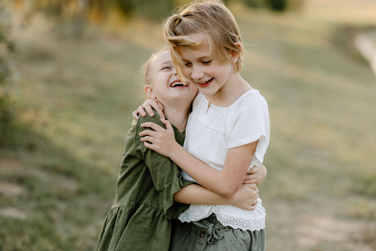 sweet candid picture of 2 sisters laughing and hugging during fall family pictures