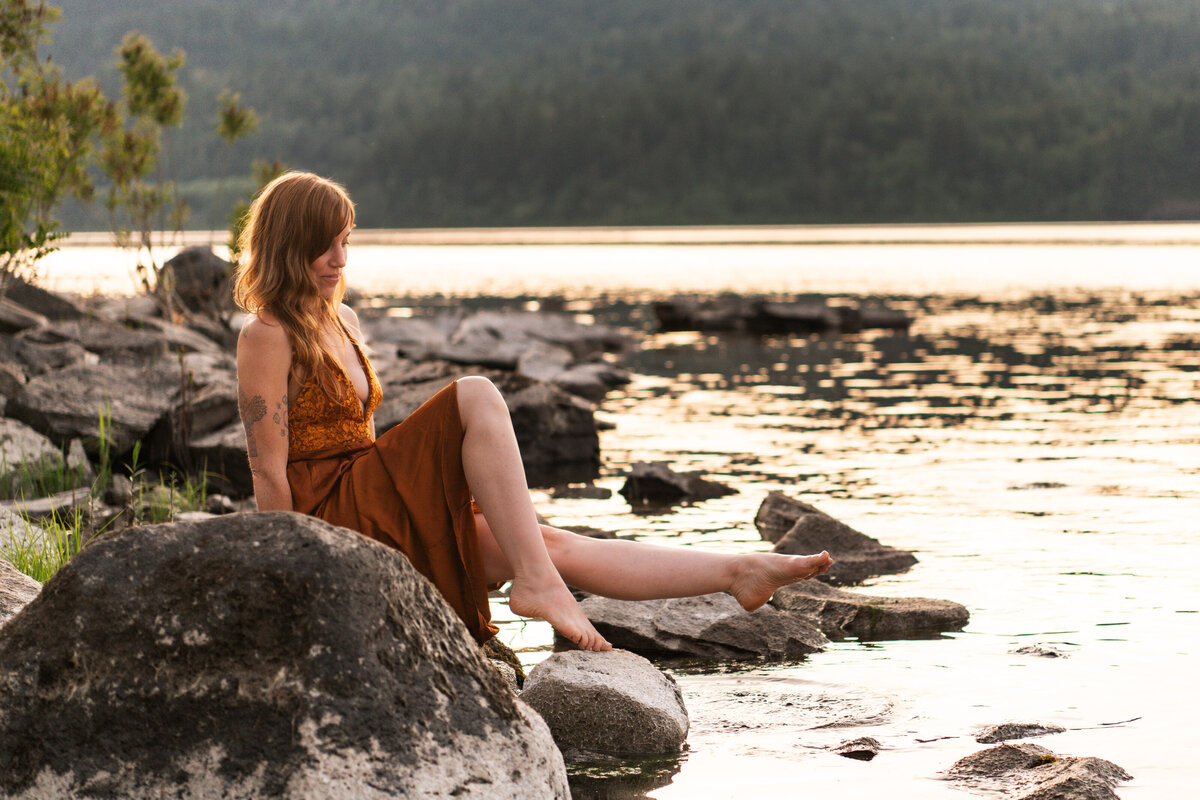 mentor, healer, guide sitting on river rock with her leg extended