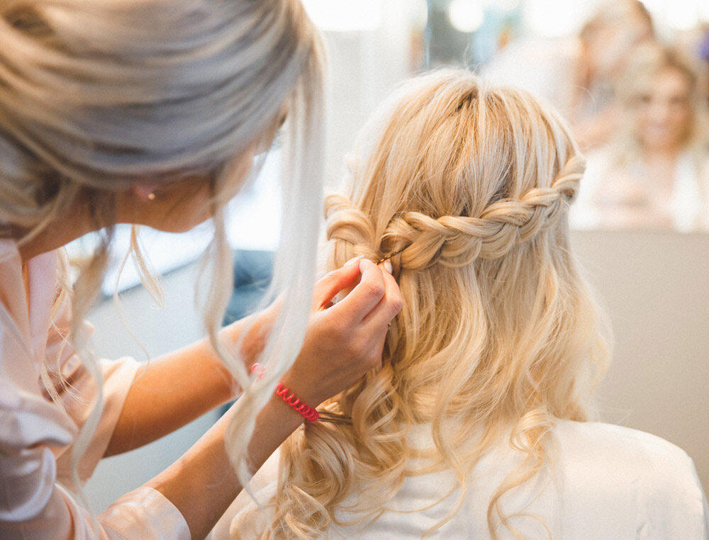Stylist pins the back of blonde bride's hair