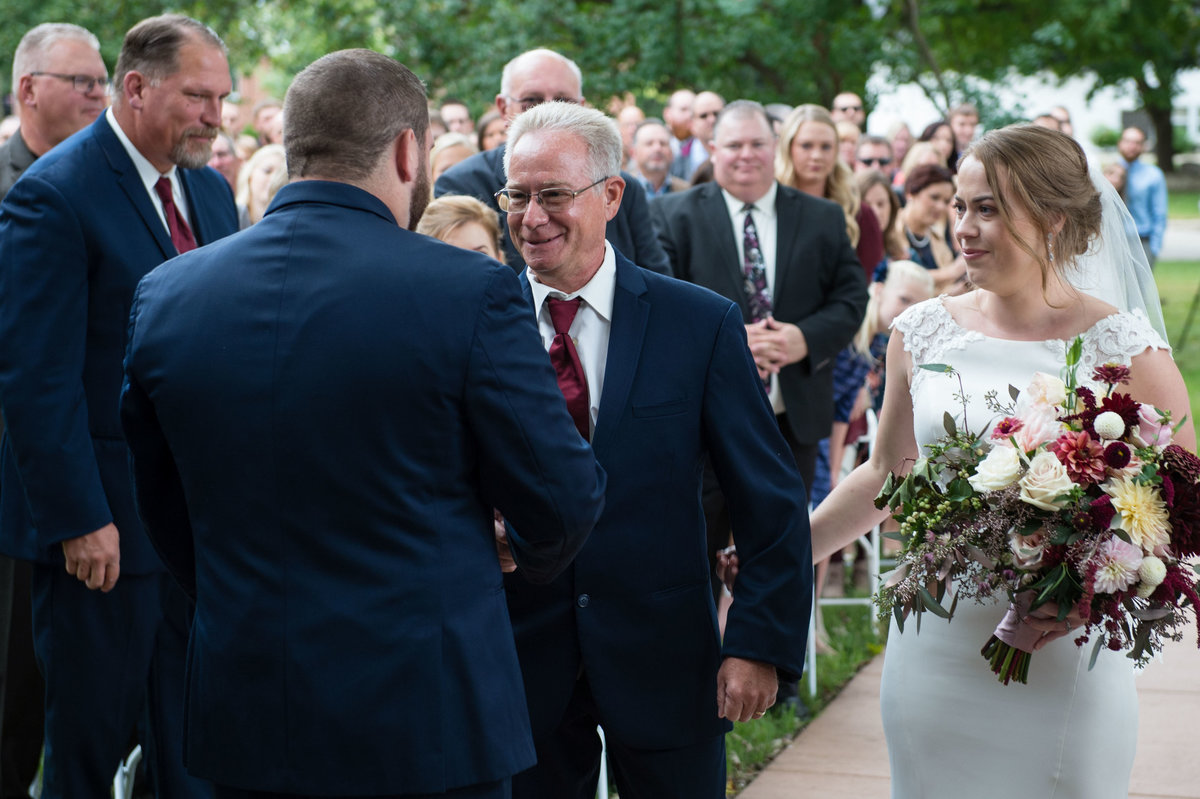 father shakes hands with groom
