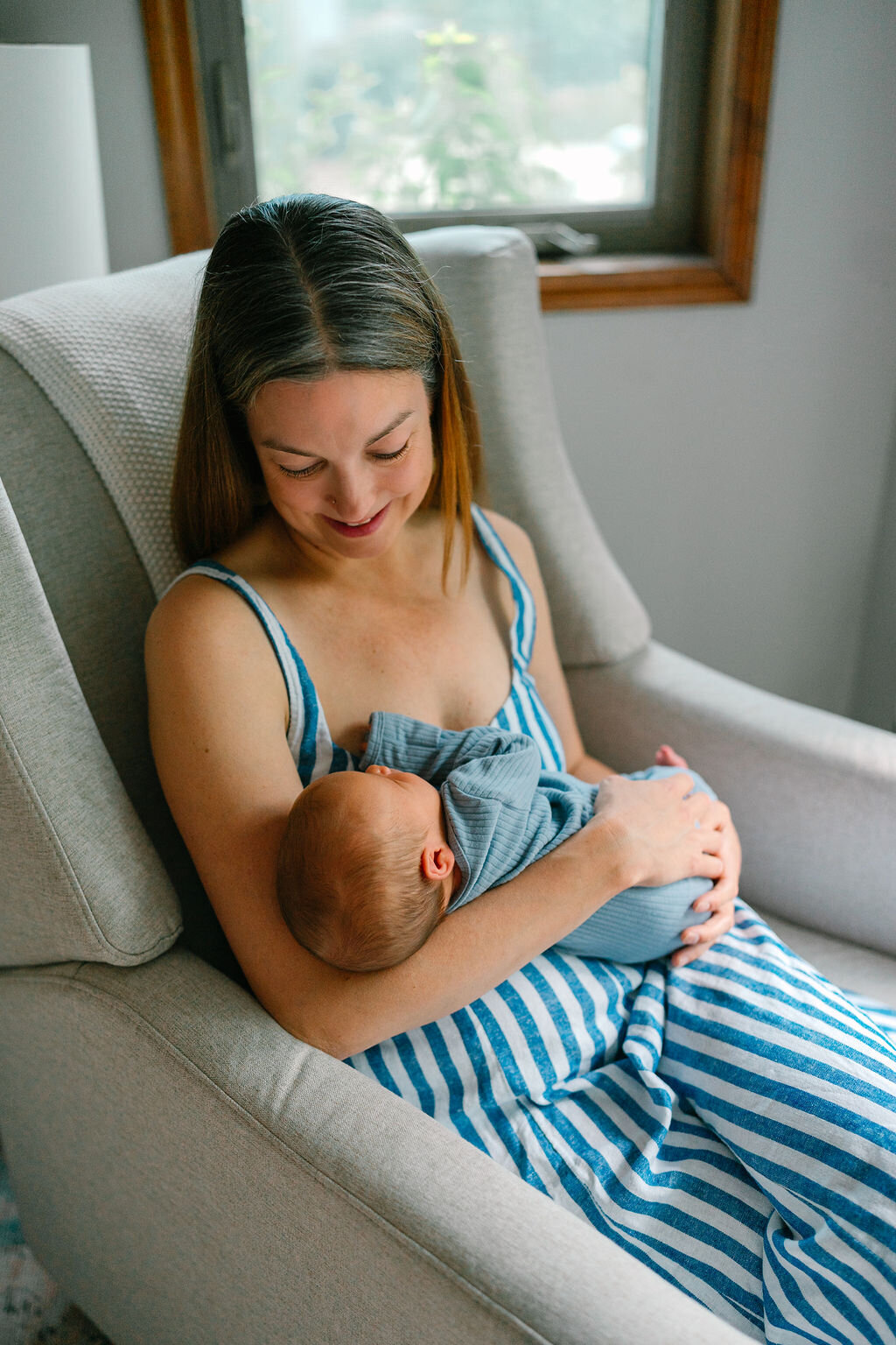 A parent holding their child while sitting down and smiling at them 