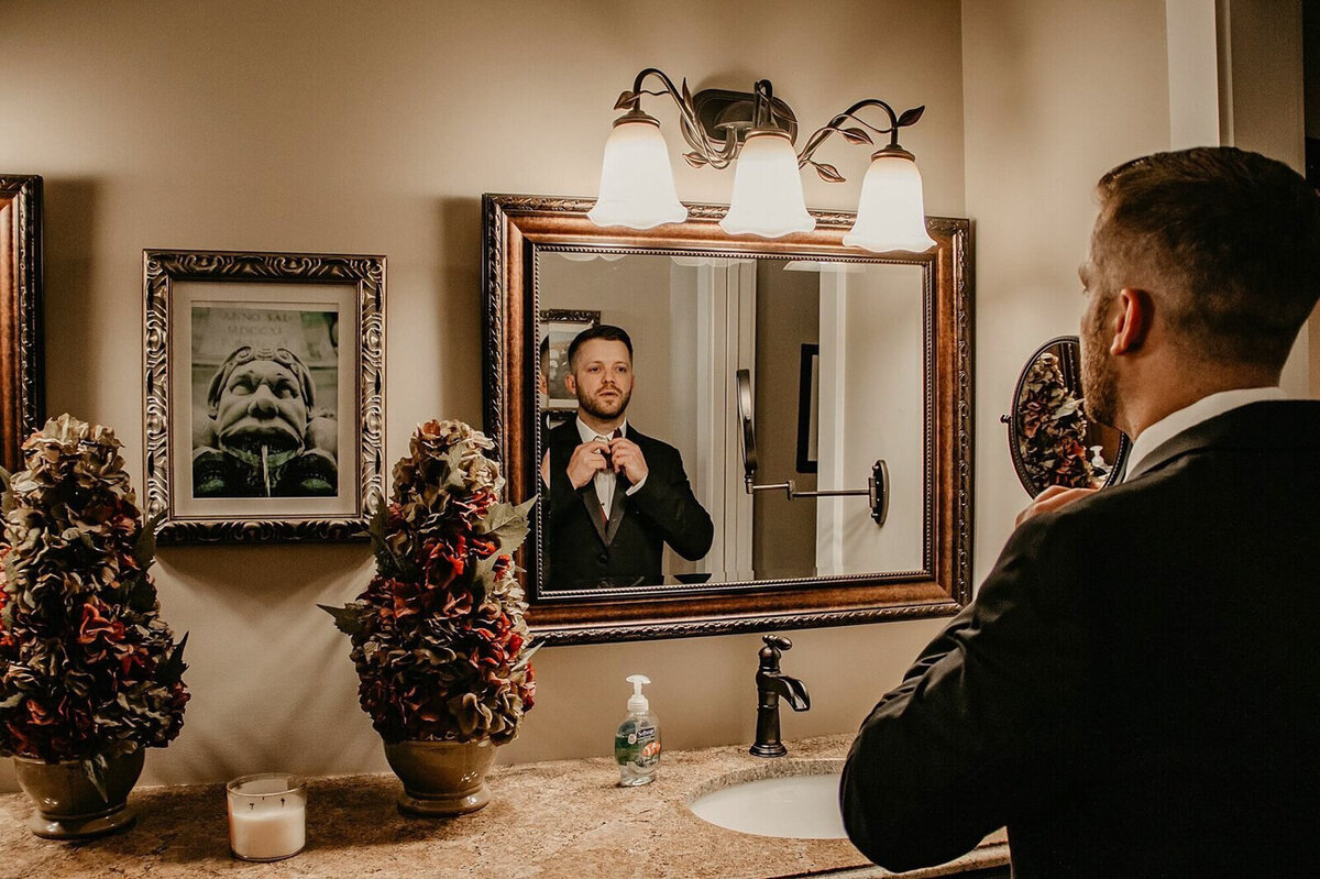 storyteller-collective-photo-co-groom-getting-ready-mirror-whispering-waters-venue-new-london-missouri