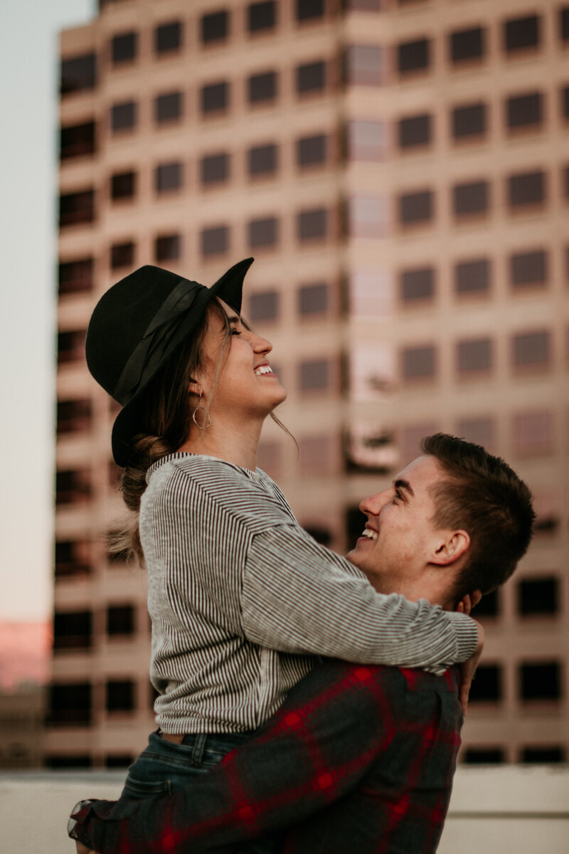 man picking up wife on a rooftop laughing