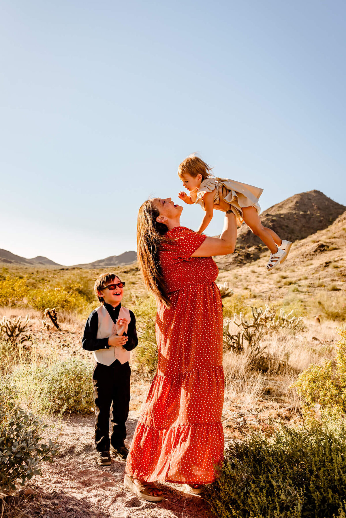 mom playing with daughter and son in Arizona desert for family photographs