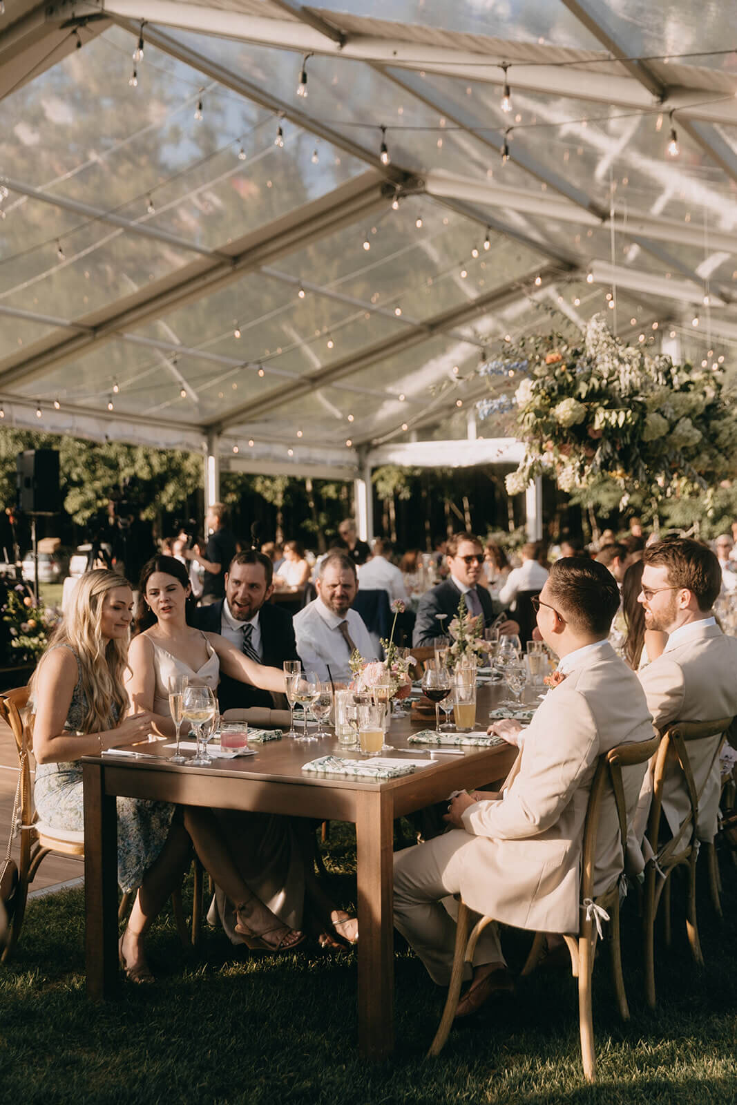65.clear-tent-wedding-reception-string-lights-guests-enjoying-dinner.