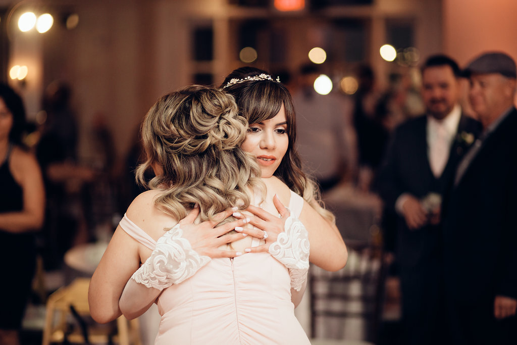 Wedding Photograph Of a Woman In Peach Dress Hugging The Bride Los Angeles