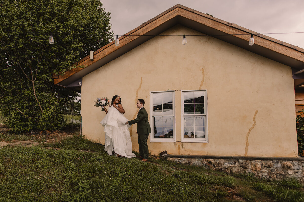 A wedding couple walking up a small grass hill together 