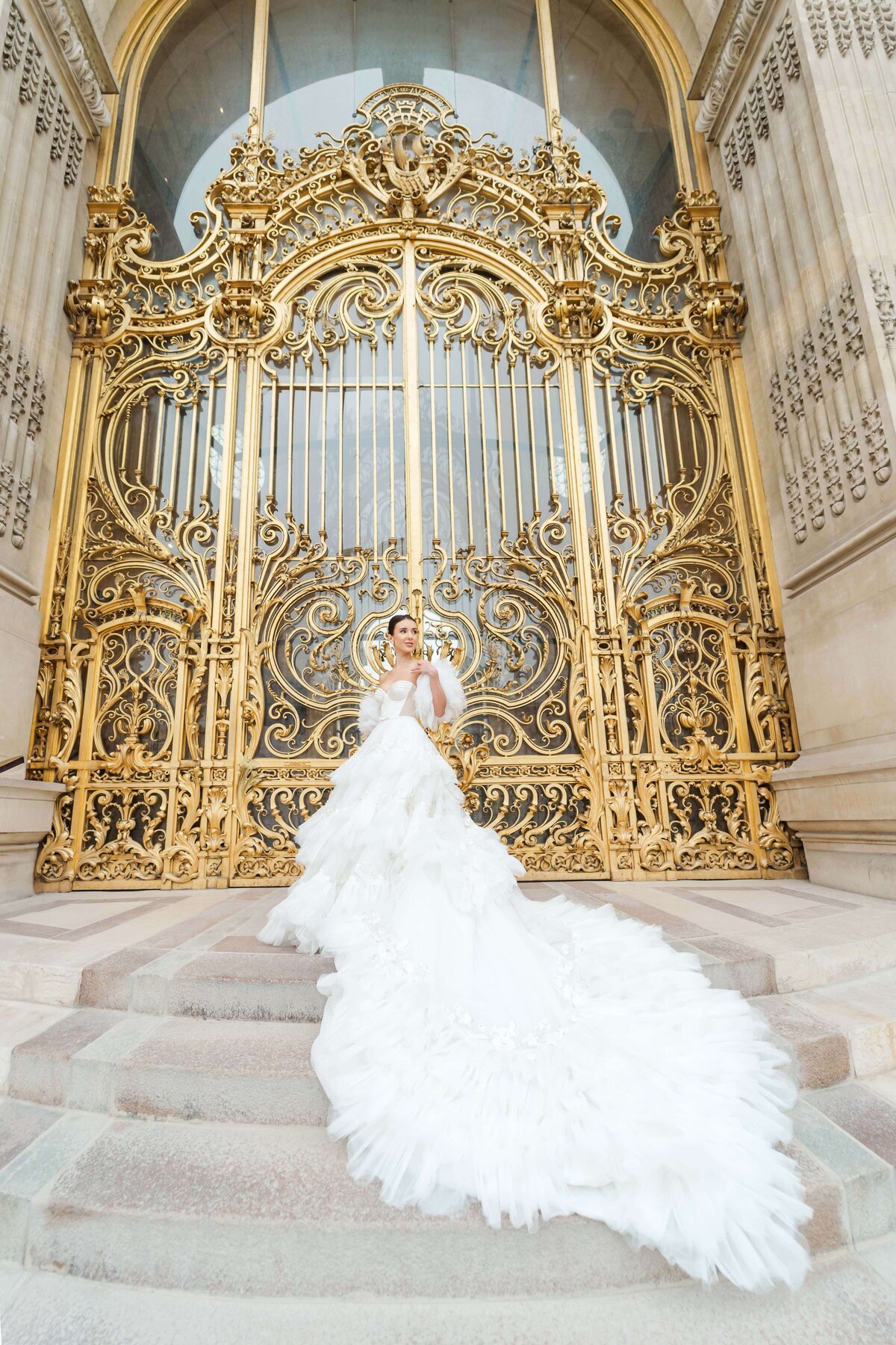 bride standing on her  weeding dress in front of the golden doors of Paris
