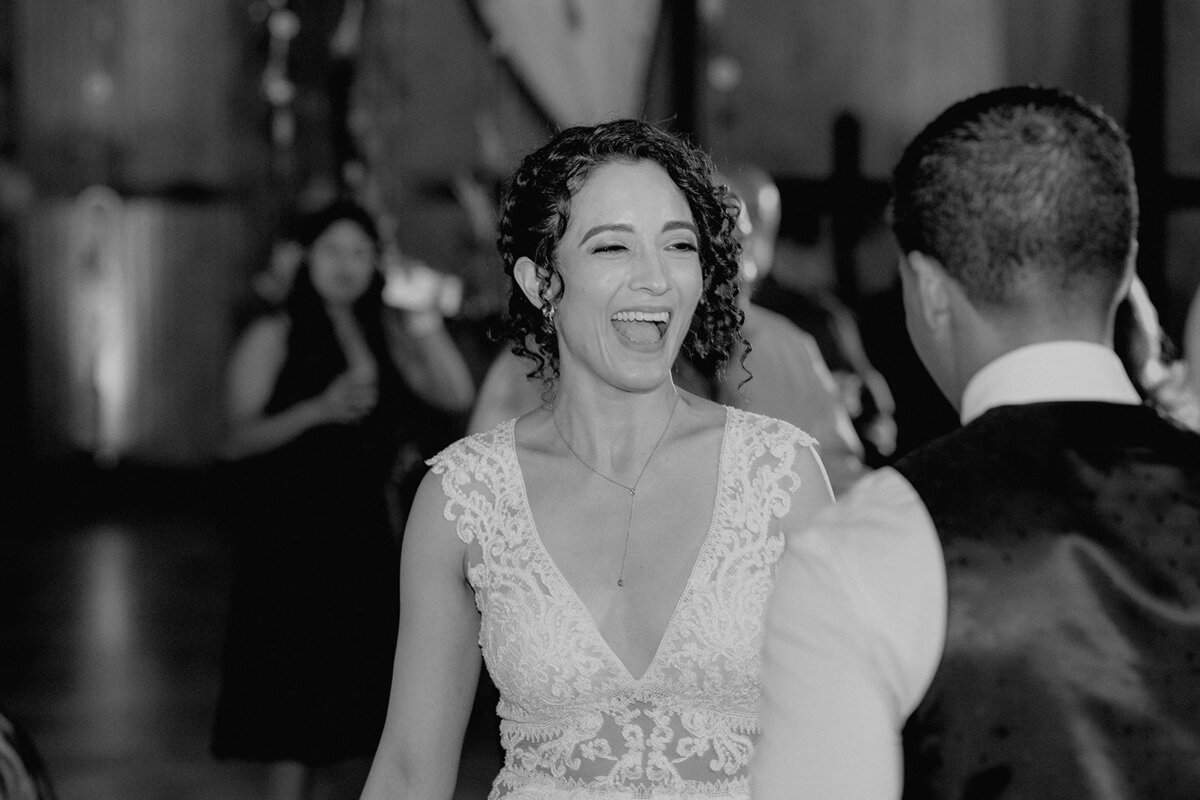 A black-and-white image of the bride laughing as she dances with her groom, capturing a candid moment of joy.