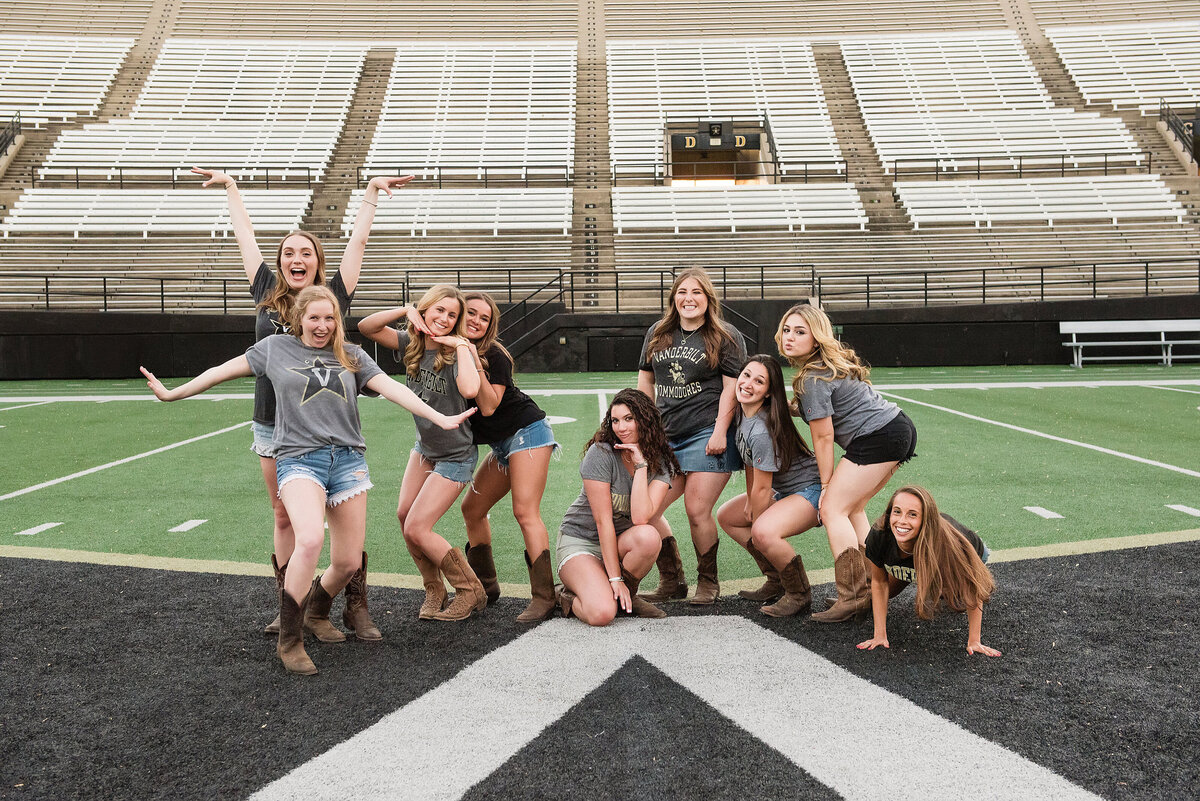 Group photo of senior girls laughing and having fun together of the college football field