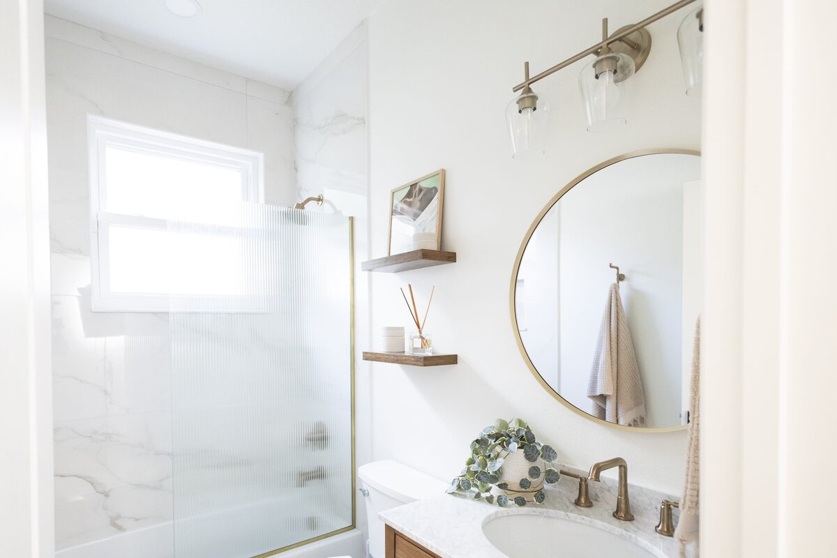 dewine design orlando interior designer belle isle bathroom with wooden floating shelves and gold trimmed round mirror