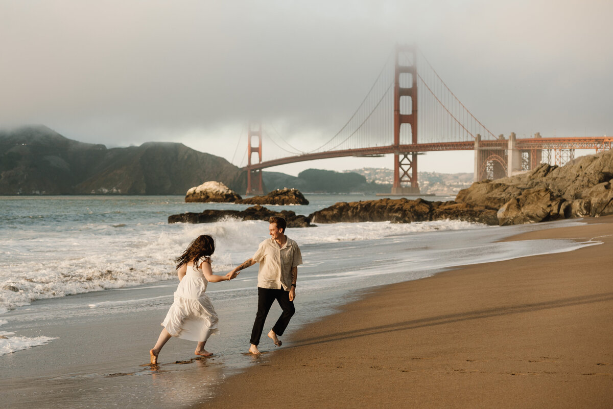 couple running under golden gate bridge