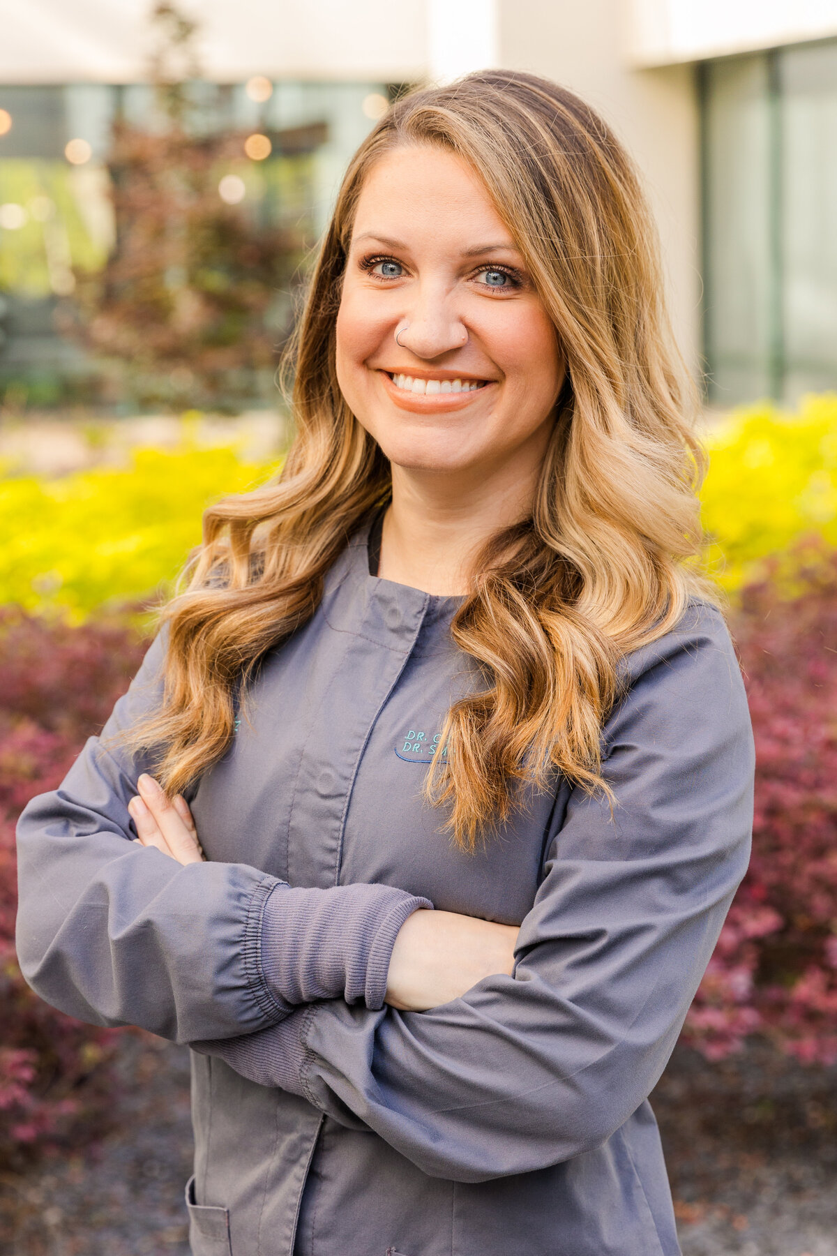 woman wearing a gray doctor blouse standing arms crossed in a garden Atlanta GA during portraits session