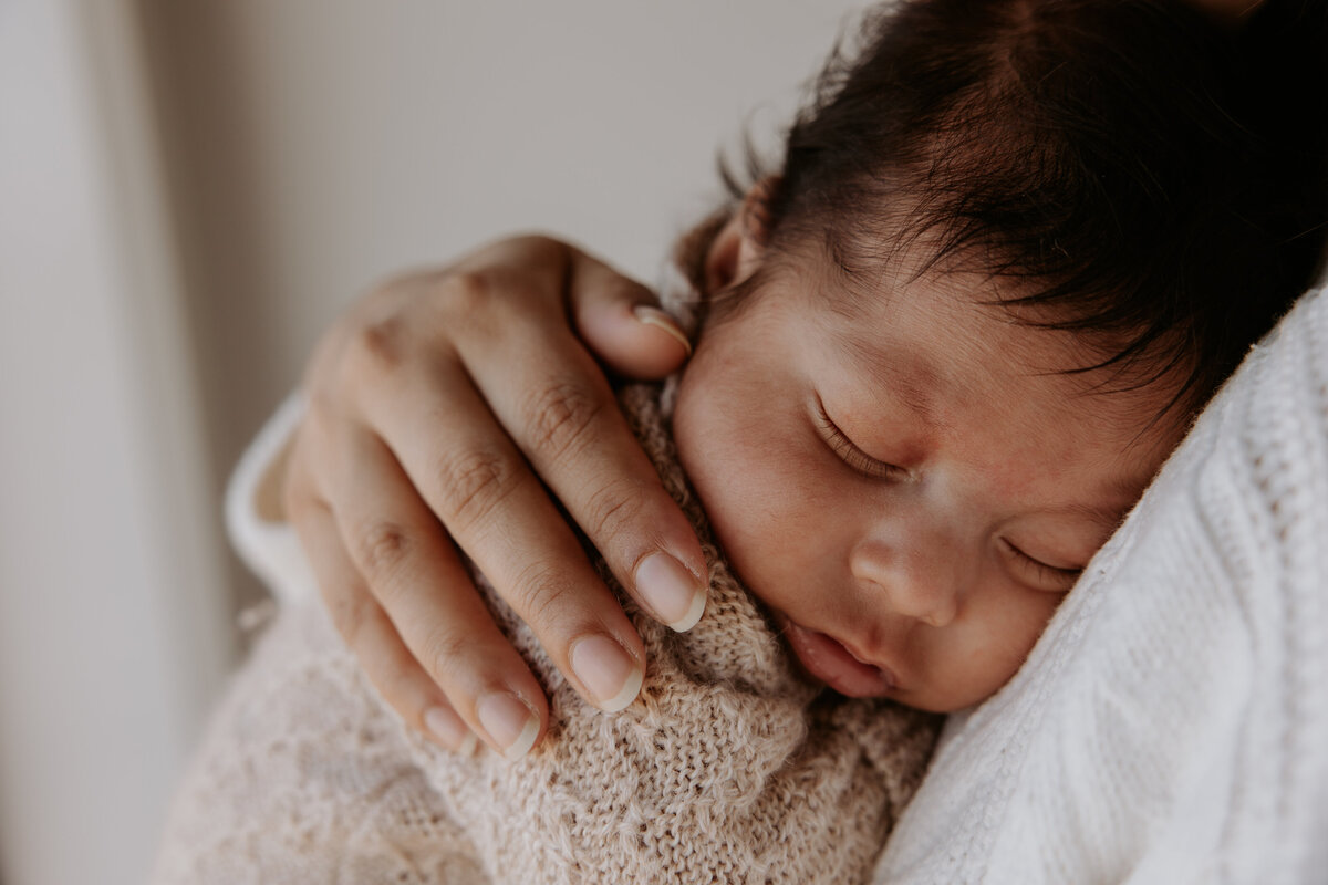 Newborn baby snuggles into parents chest