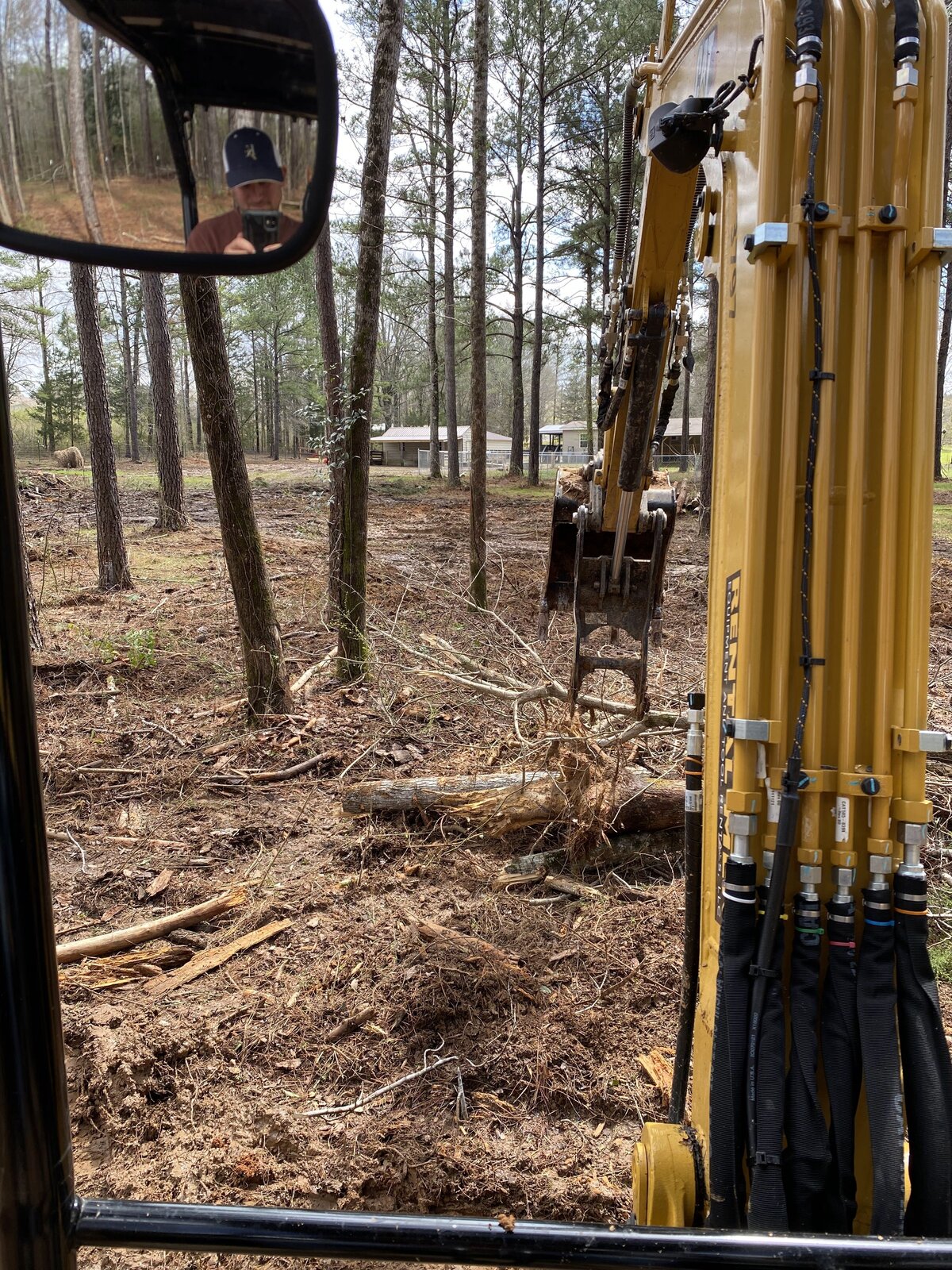 man-taking-photo-inside-excavator-while-clearing-trees