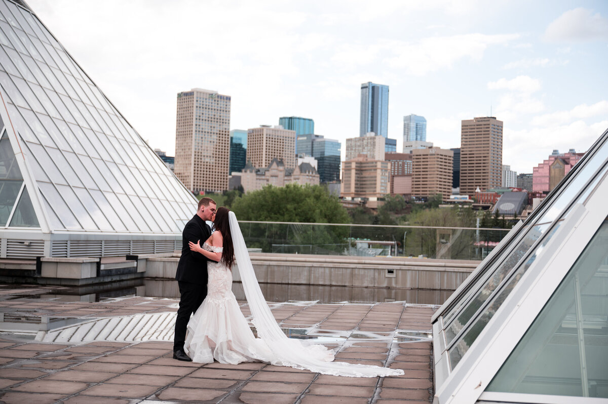 bride and groom kissing, background showcasing downtown Edmonton skyline