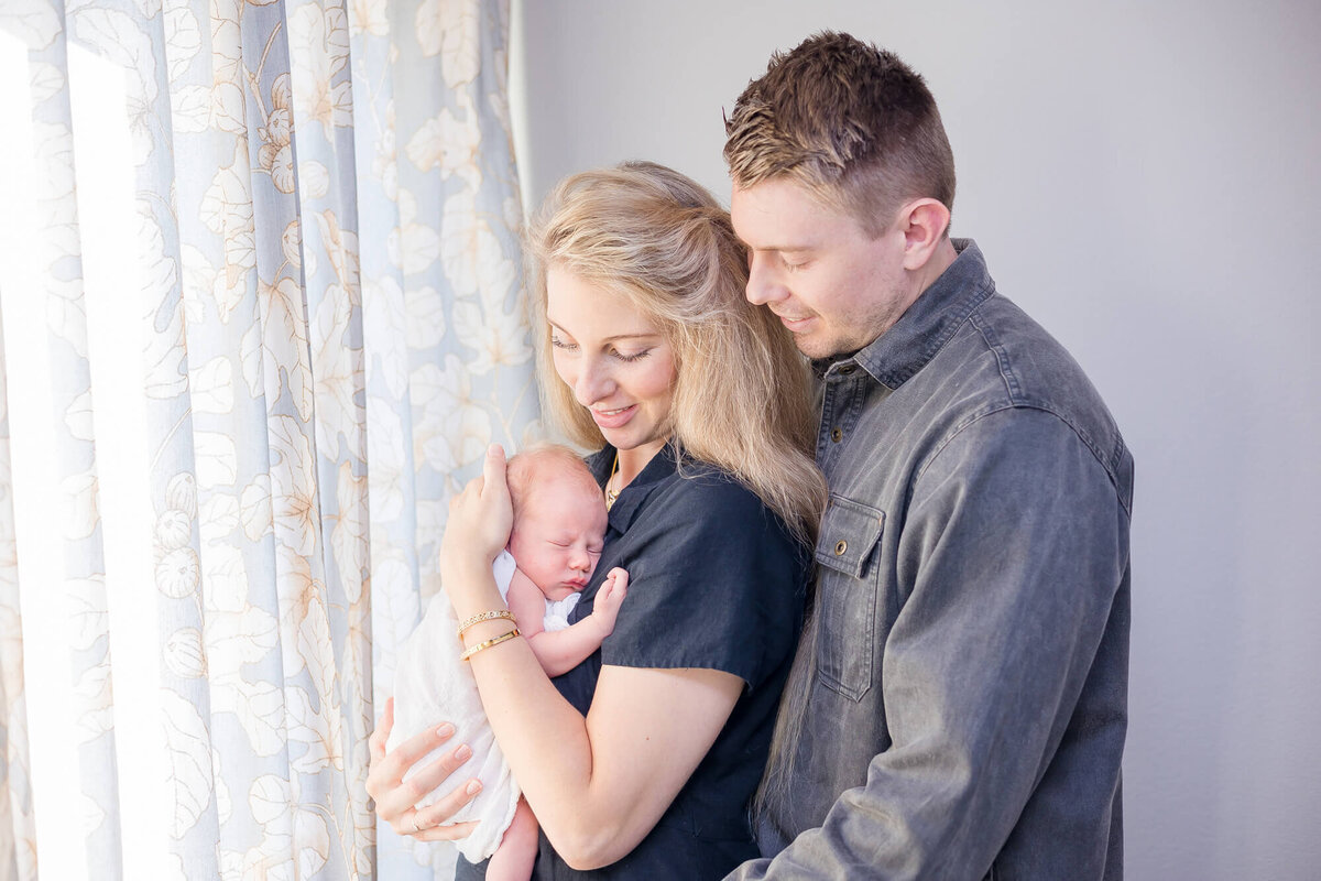 Couple happily holding their newborn son during their las vegas newborn photography session