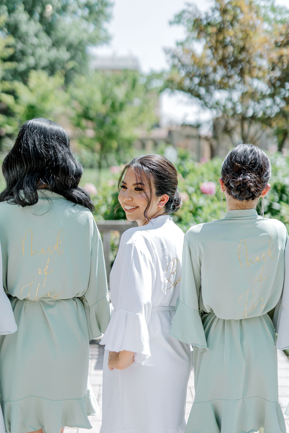 Bride with bridesmaids in robes, smiling outdoors