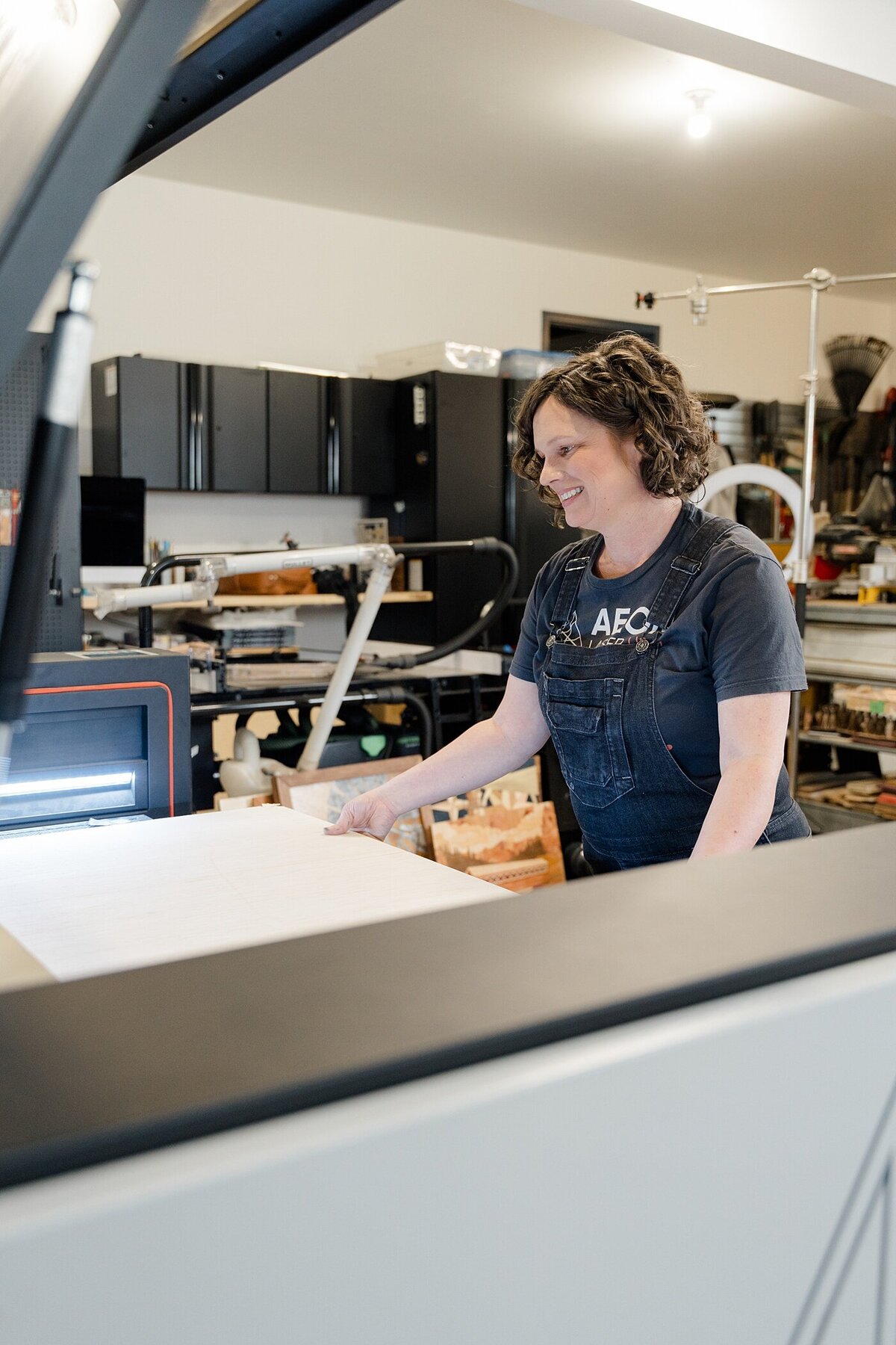 woman working in a wood shop on a laser machine for personal branding photography