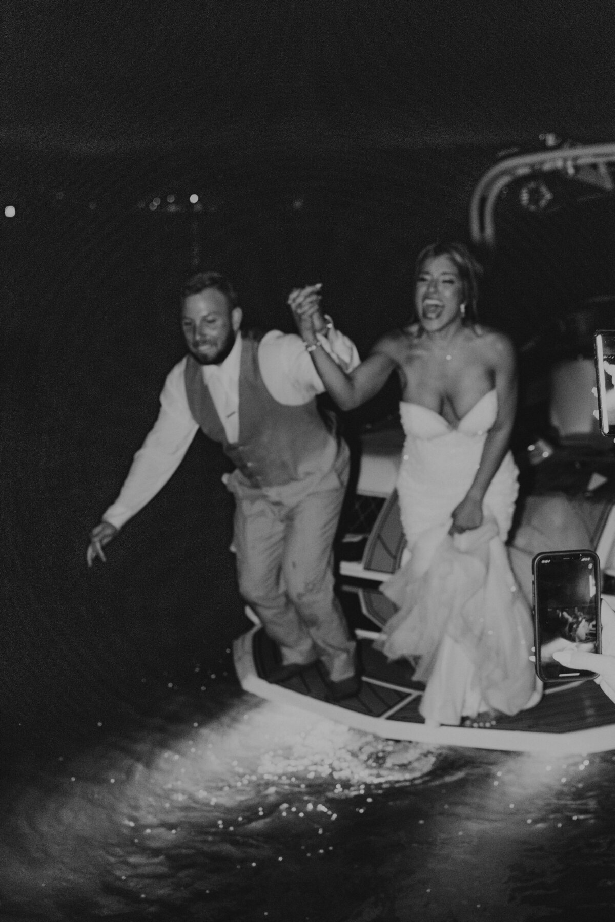 bride and groom jumping from boat on wedding day