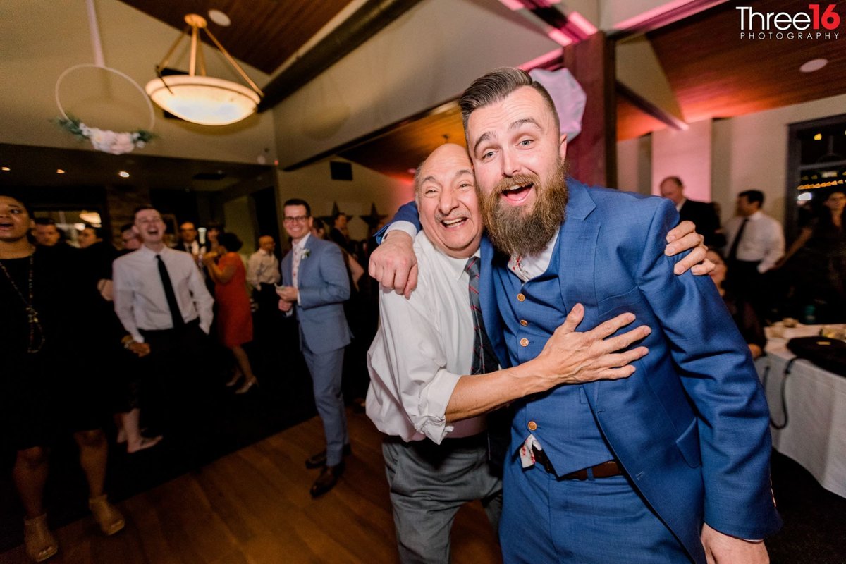 Groom poses with wedding guest on the dance floor
