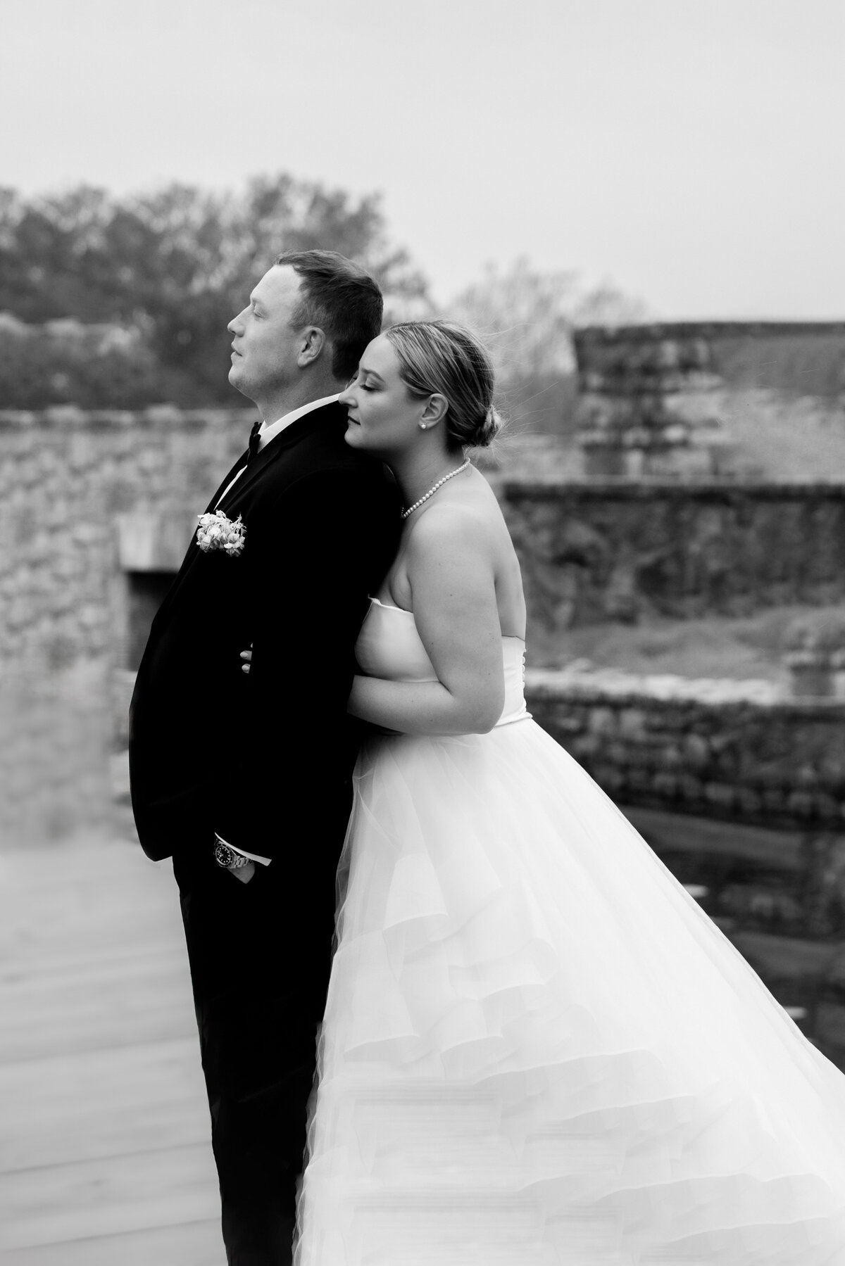 Bride and groom hugging and looking over lake