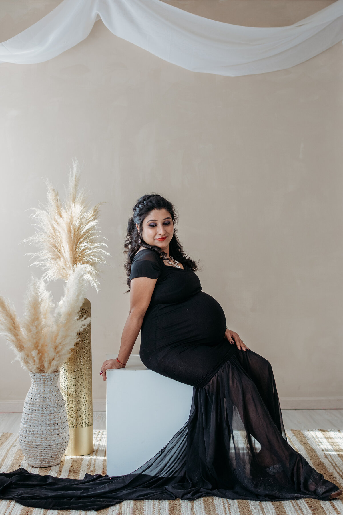 Glowing mom to be in a black maternity gown in a studio in WInfield, IL
