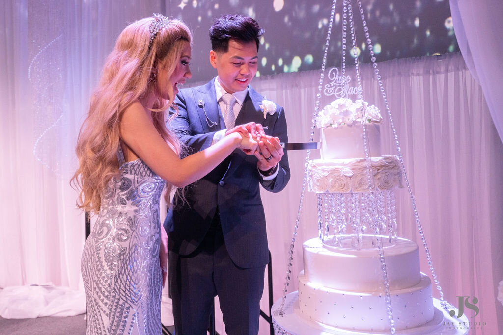 Bride and groom cut their white hanging wedding cake.