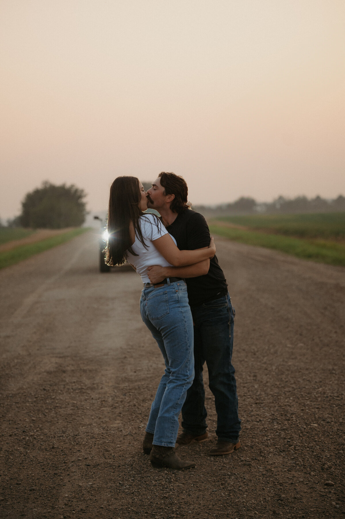 Couple kissing in front of truck on an old dirt road after sunset in Edmonton