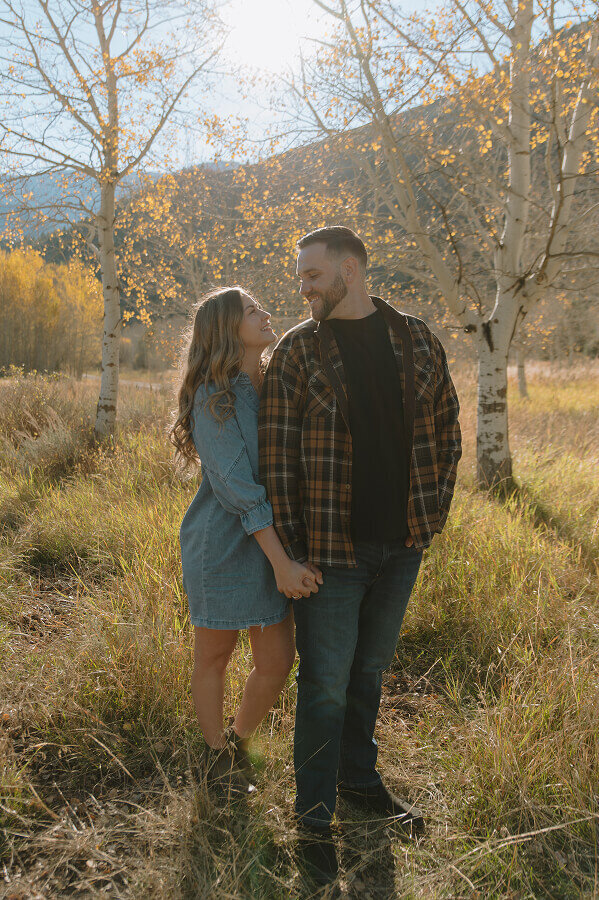 A man and woman hold hands as they look into each other's eyes for their engagement shoot in Swan Valley ID.