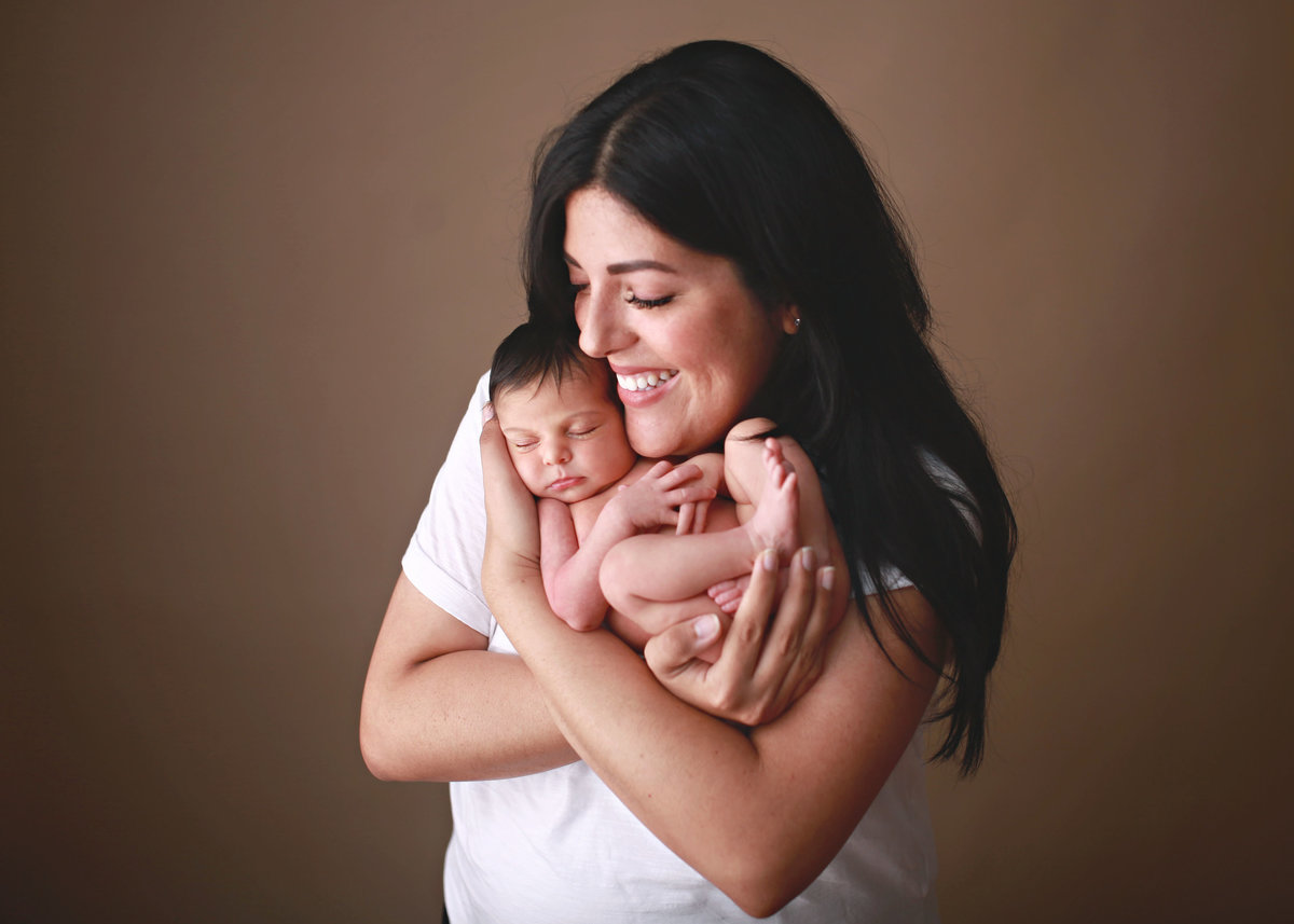 smiling mother holding newborn baby close to face