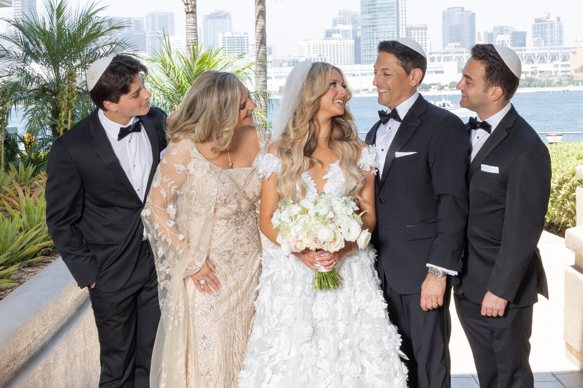 A bride smiling and standing with her family