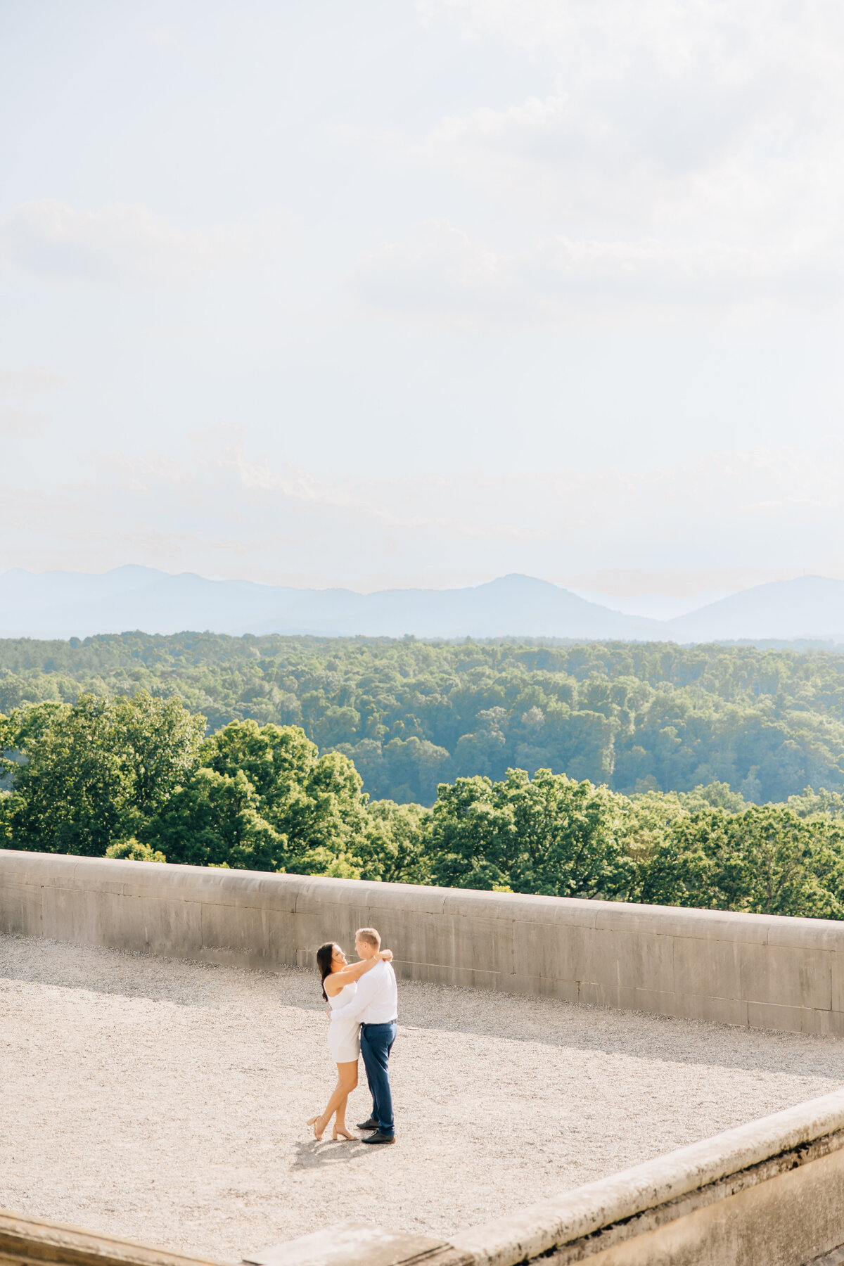 couple hugging at biltmore estate with views of the mountains in the background
