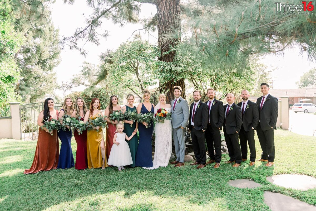 Wedding party poses with the Bride and Groom under a large tree