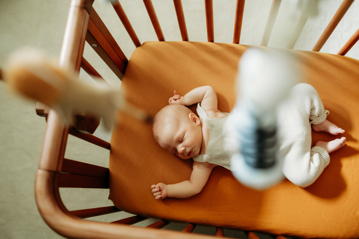 A baby sleeps peacefully on a cozy, neutral-toned bed while parents look on lovingly, capturing the essence of in-home luxury.