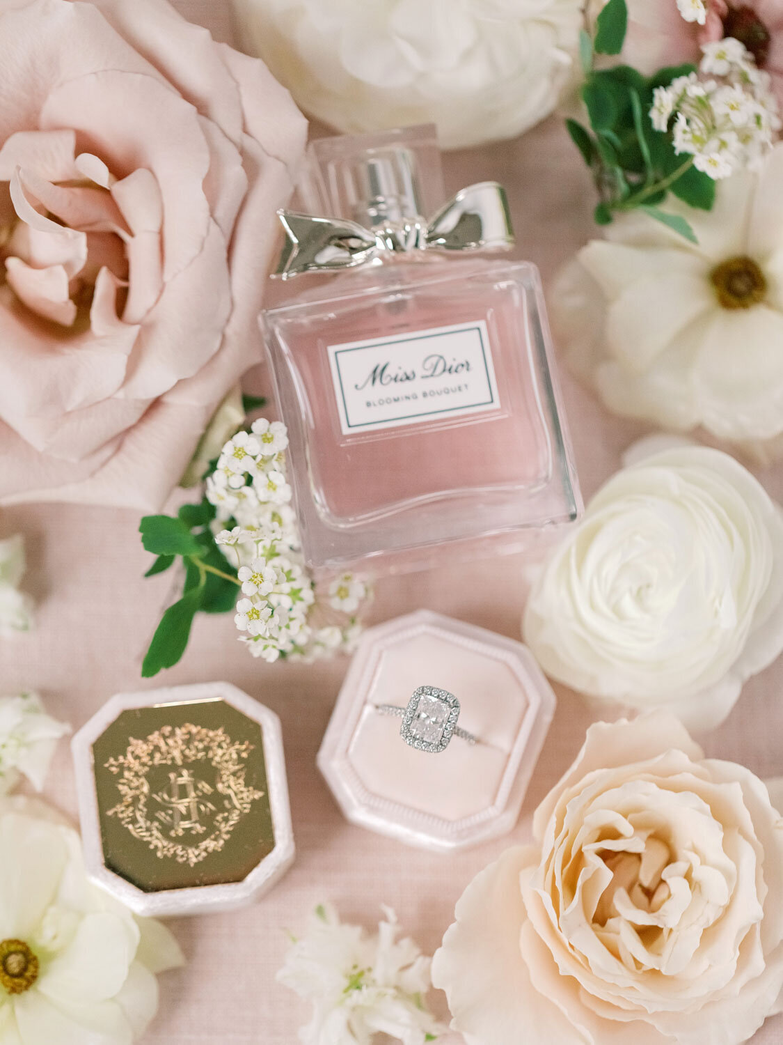 Flat lay of Miss Dior perfume, ring, and flowers