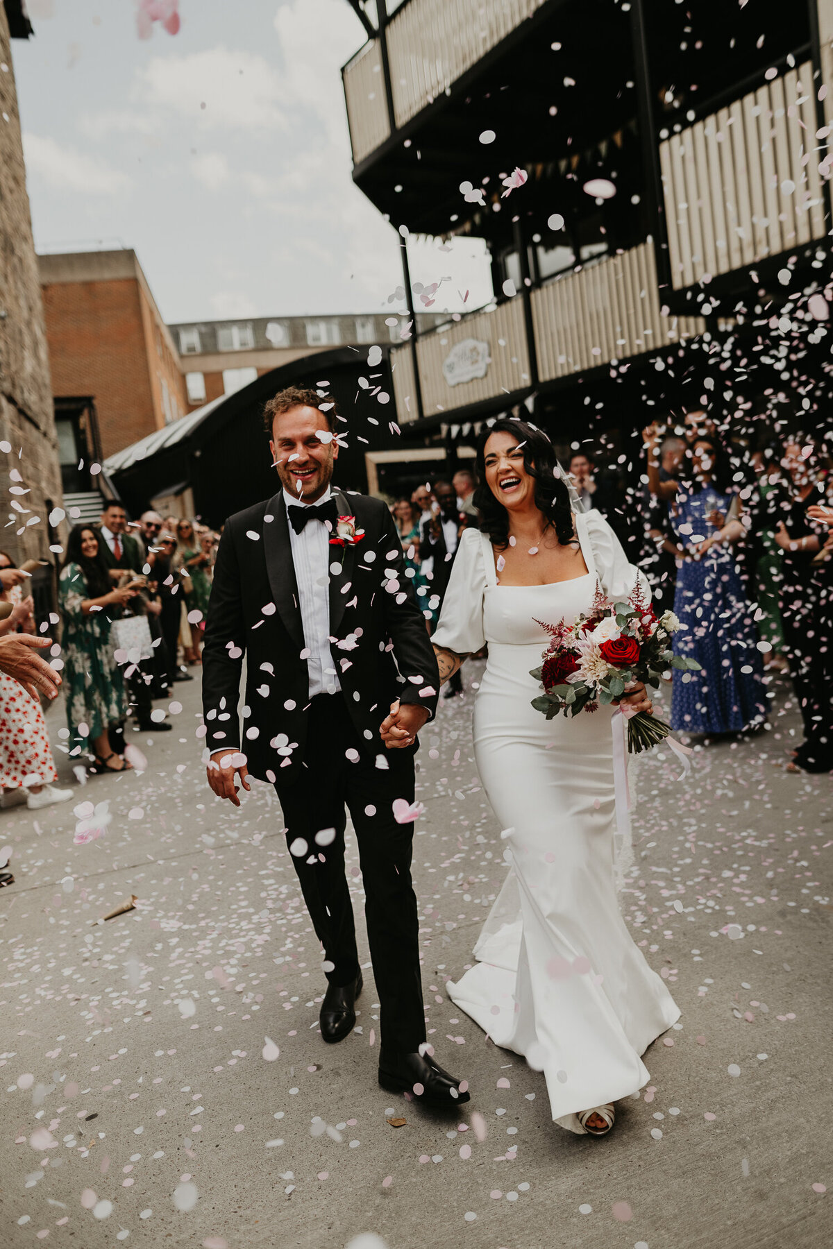 A Bride and Groom walk through a confetti tunnel at The Shack Revolution.