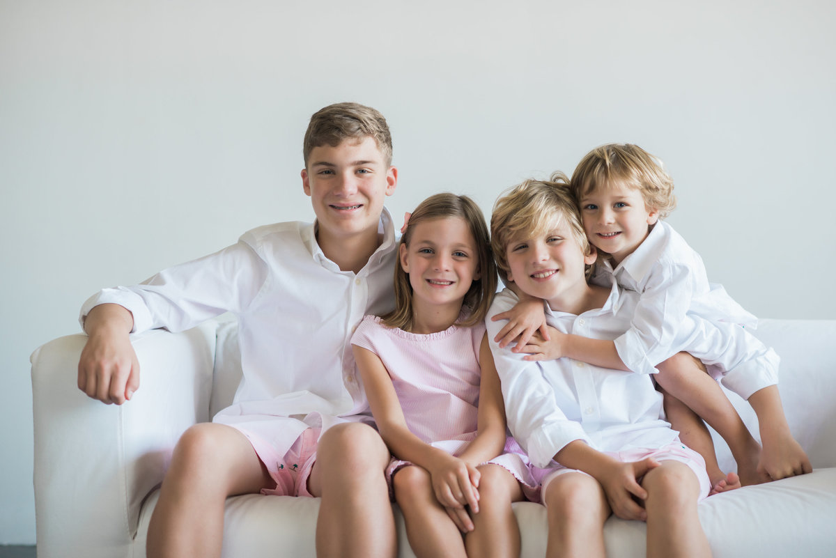 sister in pink seersucker sitting with three brothers in white button downs