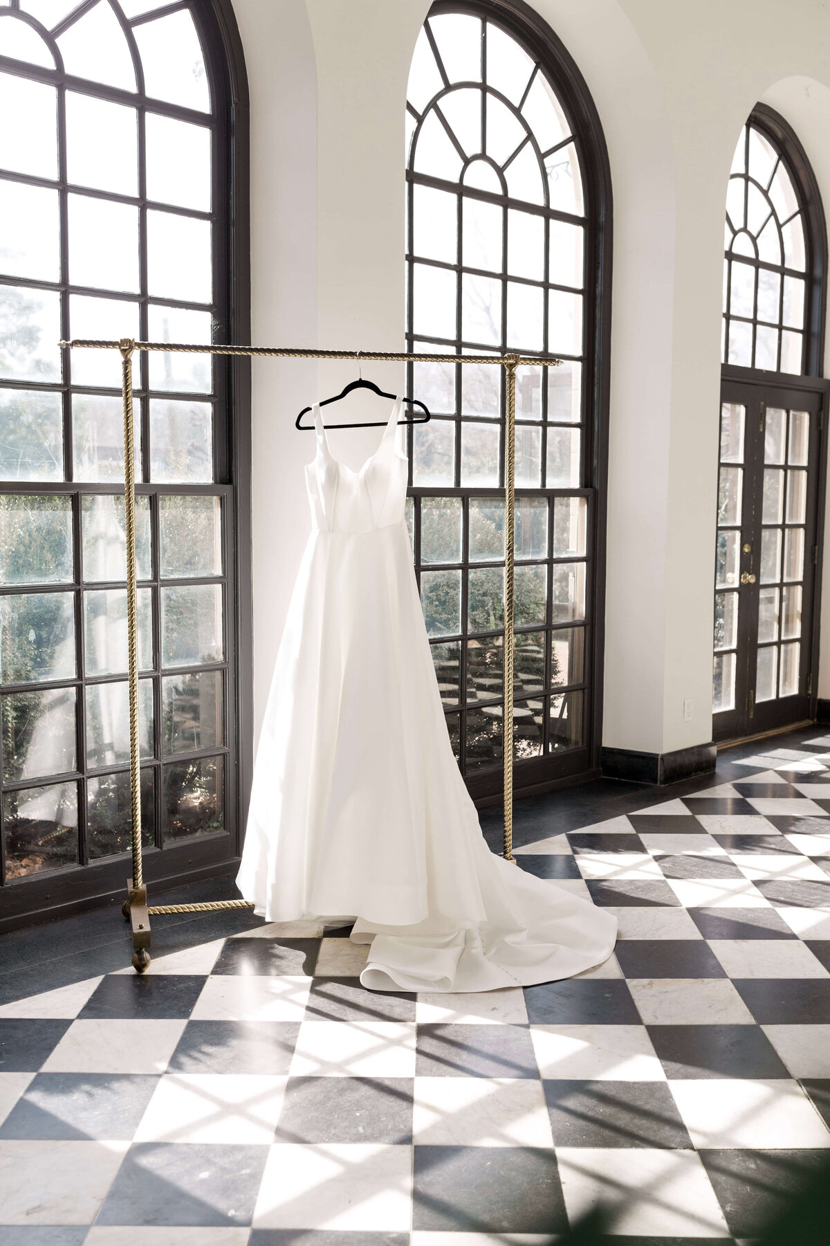Wedding gown hanging  in front of large windows